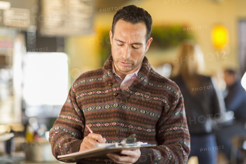Hispanic businessman writing in coffee shop