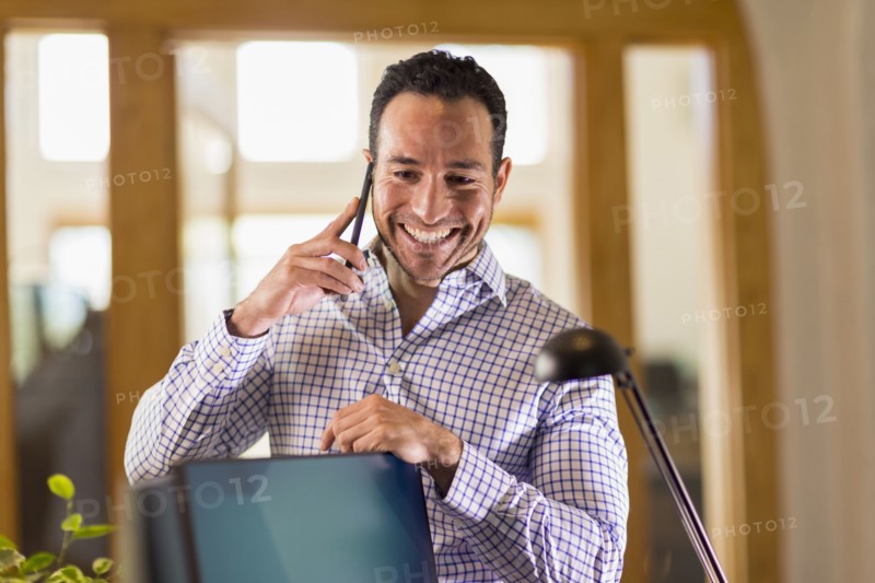 Hispanic businessman talking on cell phone in office
