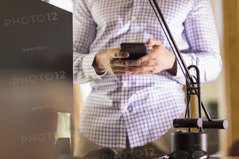 Hispanic businessman using cell phone in office