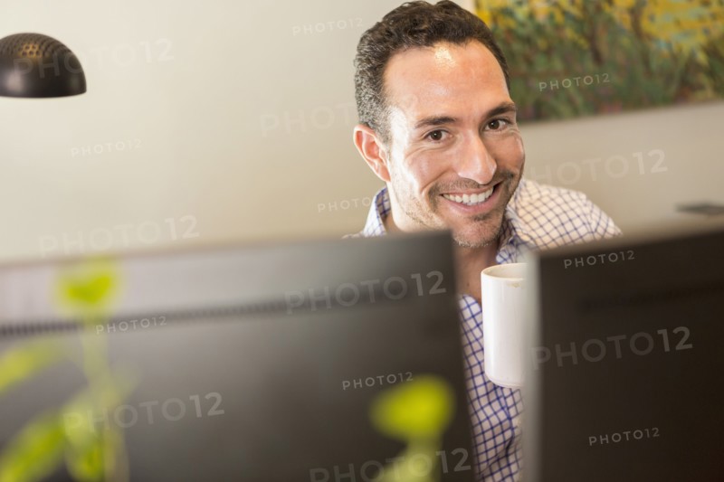 Hispanic businessman drinking coffee in office