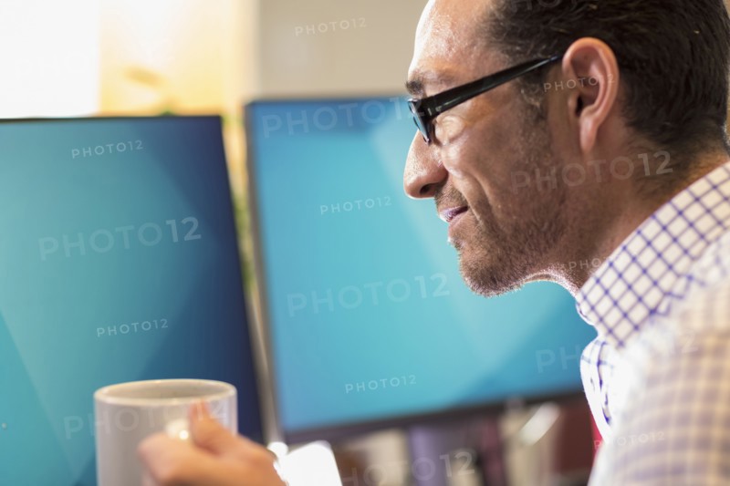 Hispanic businessman drinking coffee in office