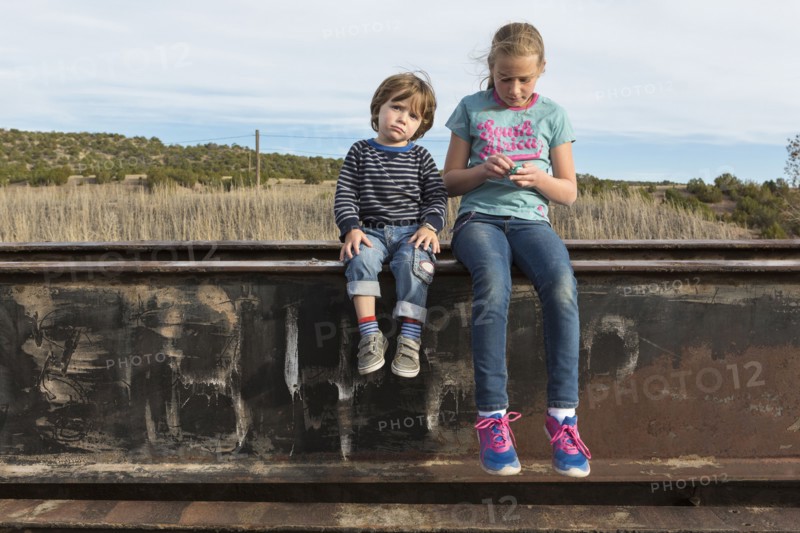 Caucasian brother and sister sitting outdoors