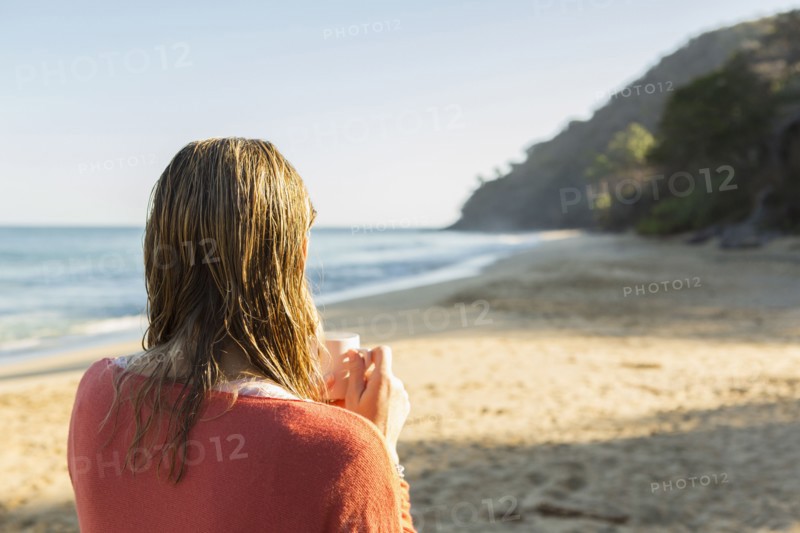 Caucasian woman drinking coffee on beach