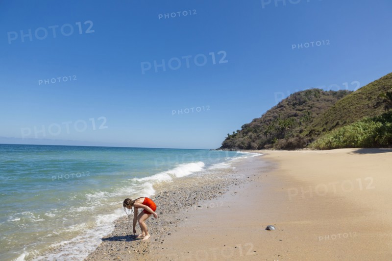 Caucasian girl examining rocks at ocean beach