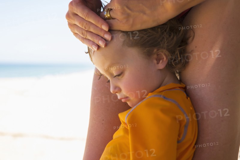 Caucasian boy leaning on legs of mother