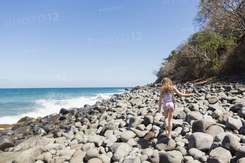 Caucasian girl walking on rocks at beach