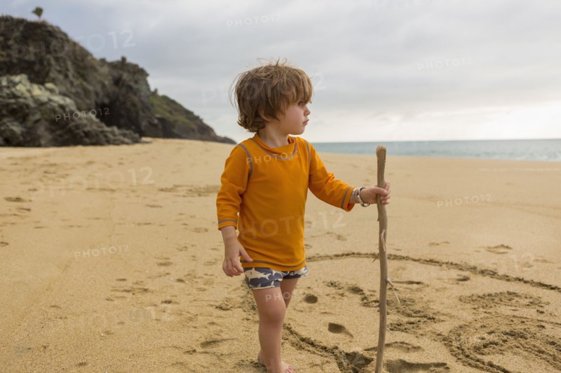 Caucasian boy with walking stick on beach