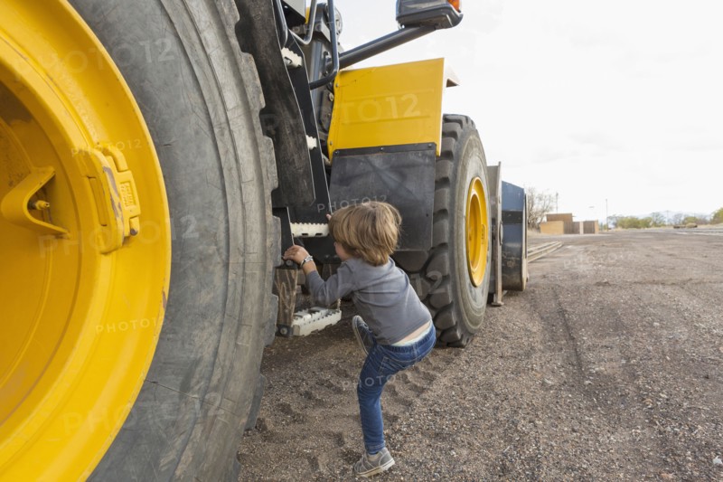 Caucasian boy climbing ladder on tractor