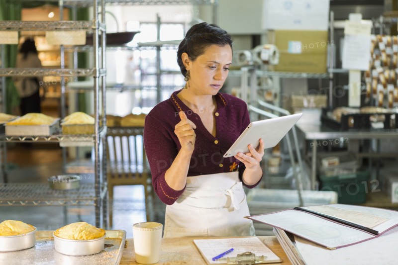 Caucasian woman using digital tablet in bakery