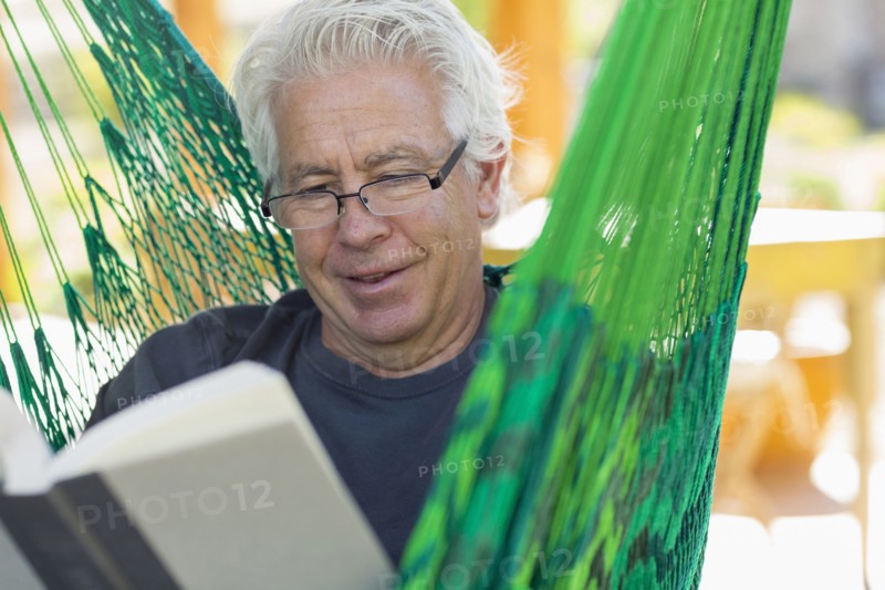 Caucasian man reading book in green hammock