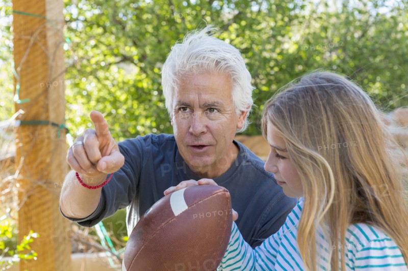 Caucasian grandfather showing granddaughter how to aim football