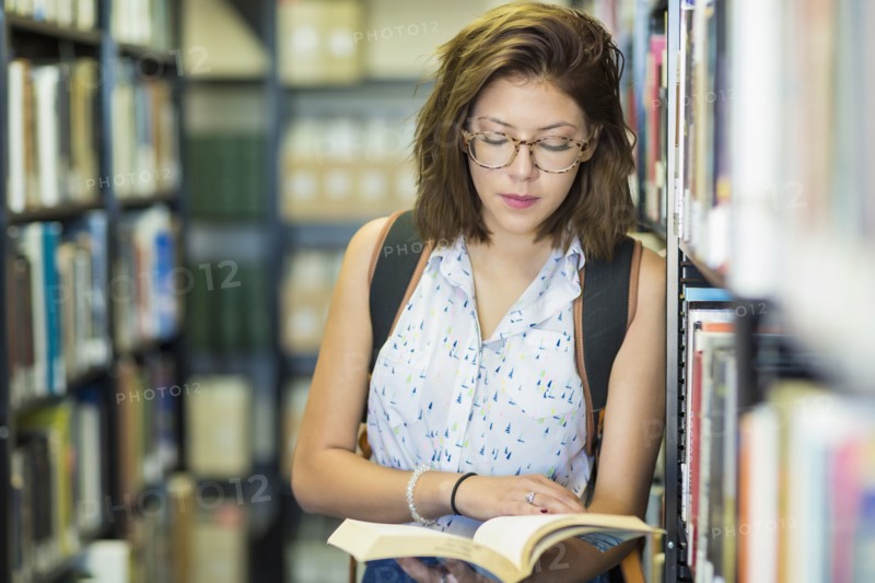 Mixed Race girl reading book in library