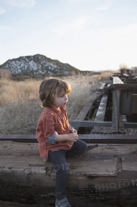Caucasian boy sitting on wood outdoors
