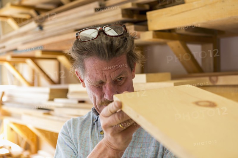Caucasian carpenter eyeballing wooden plank in workshop