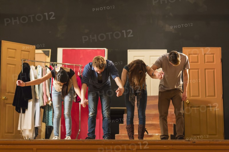 Students holding hands on stage and bowing