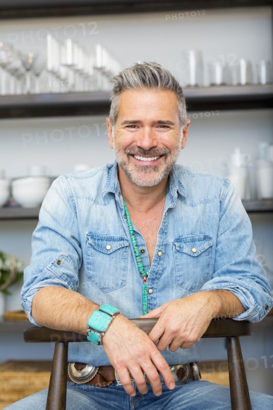 Smiling Caucasian man leaning on chair in store