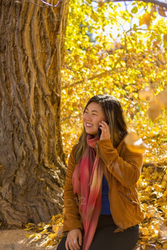 Asian woman talking on cell phone in autumn