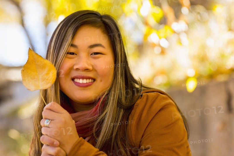 Smiling Asian woman holding leaf in autumn