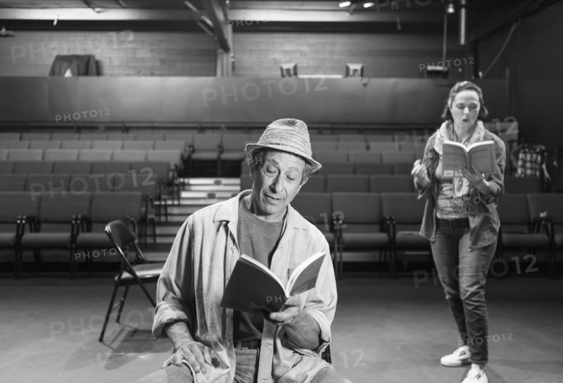 Caucasian actors rehearsing with scripts in theater