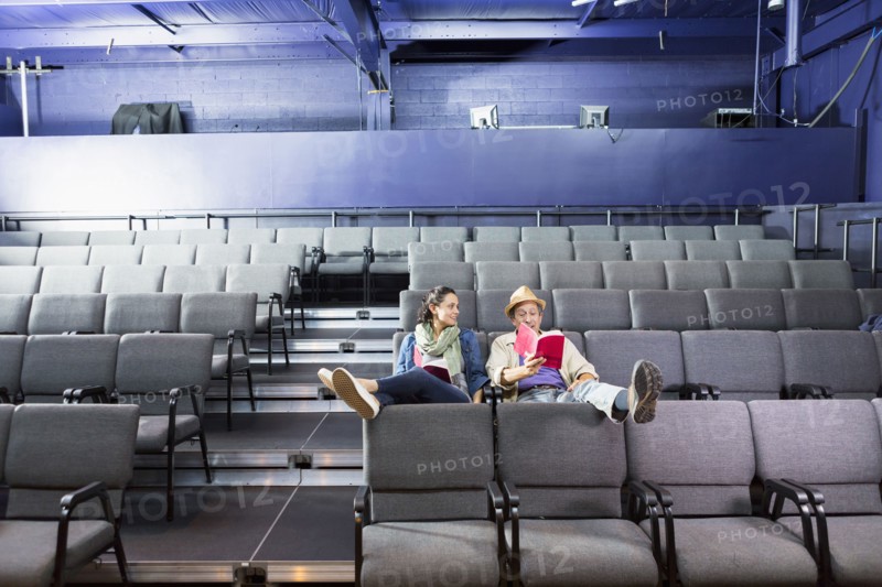 Caucasian actors sitting in audience with scripts in theater