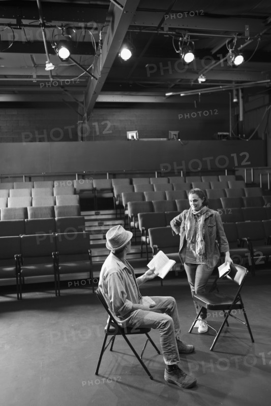 Caucasian actors rehearsing with scripts in theater