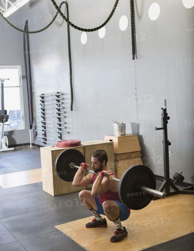 Mixed Race man lifting barbell in gymnasium