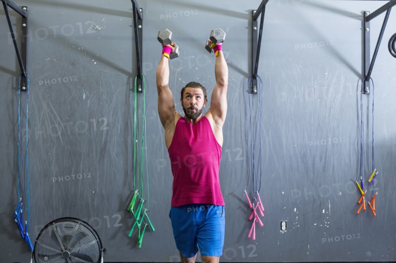 Mixed Race man lifting dumbbells in gymnasium