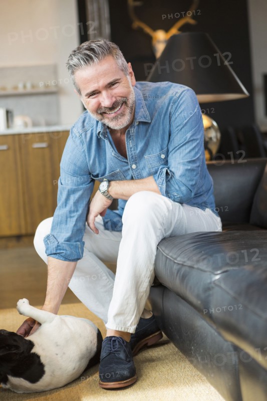 Caucasian man sitting on sofa petting dog