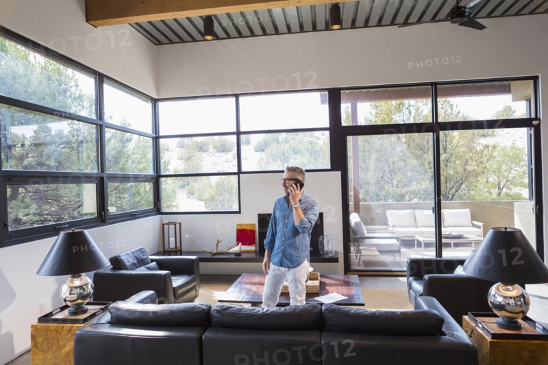 Caucasian man standing in livingroom talking on cell phone