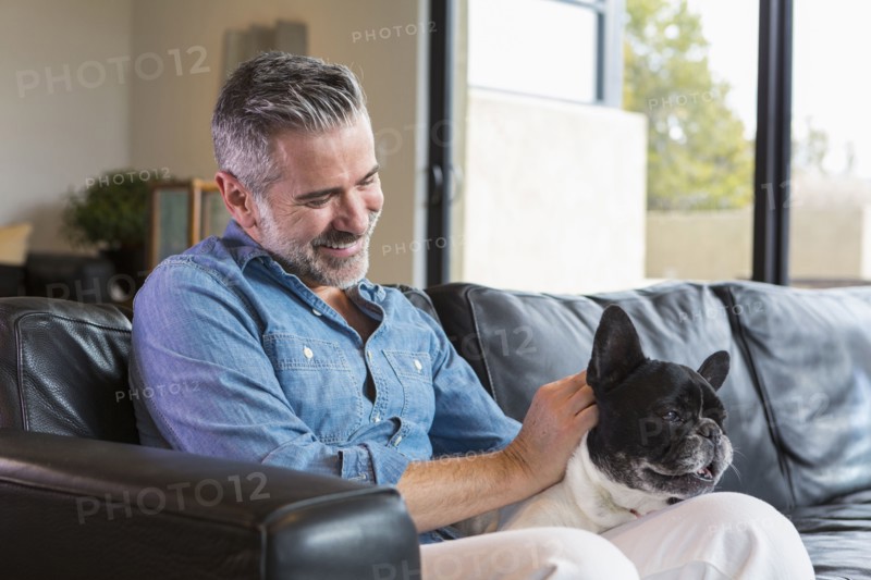 Caucasian man sitting on sofa petting dog