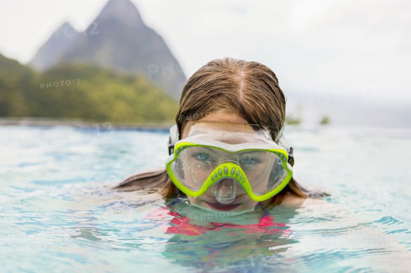 Caucasian girl wearing snorkel mask in swimming pool