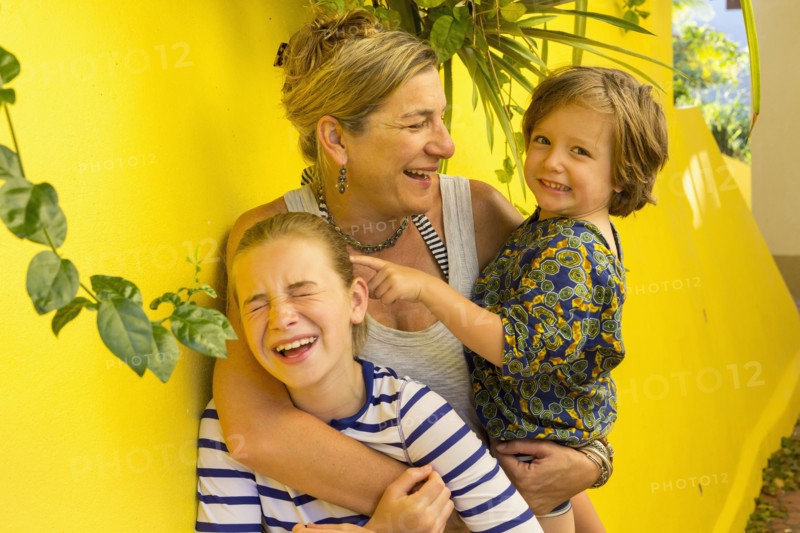Laughing Caucasian mother hugging son and daughter
