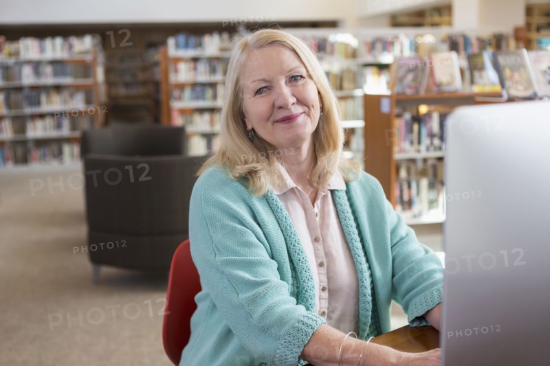 Smiling Caucasian woman using computer in library