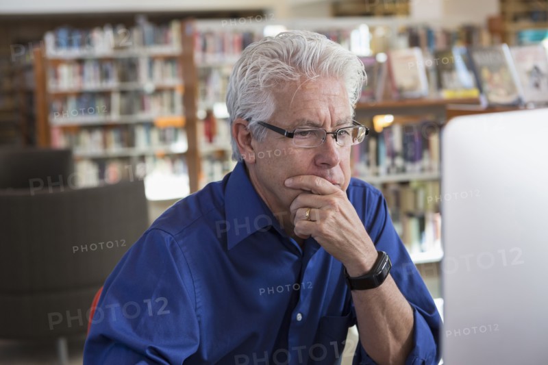 Pensive Hispanic man using computer in library