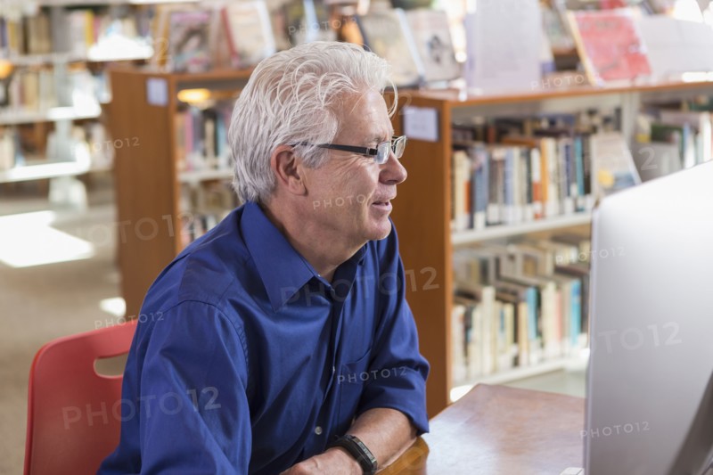 Smiling Hispanic man using computer in library