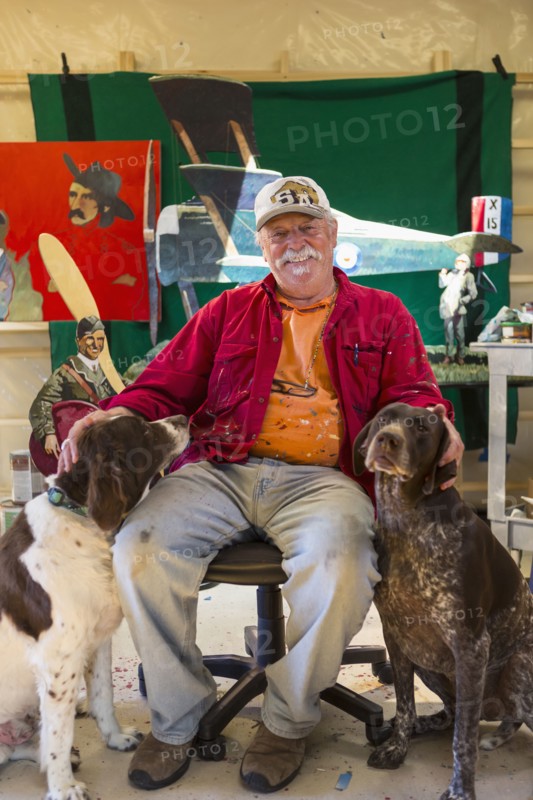 Portrait of older Caucasian man sitting in workshop with dogs