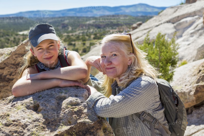 Portrait of Caucasian grandmother and granddaughter leaning on rock