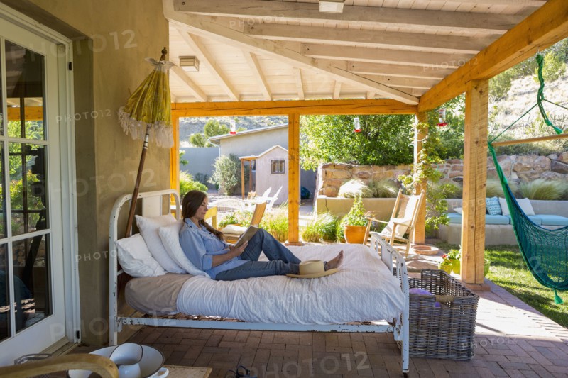 Older Caucasian woman reading books on bed on patio