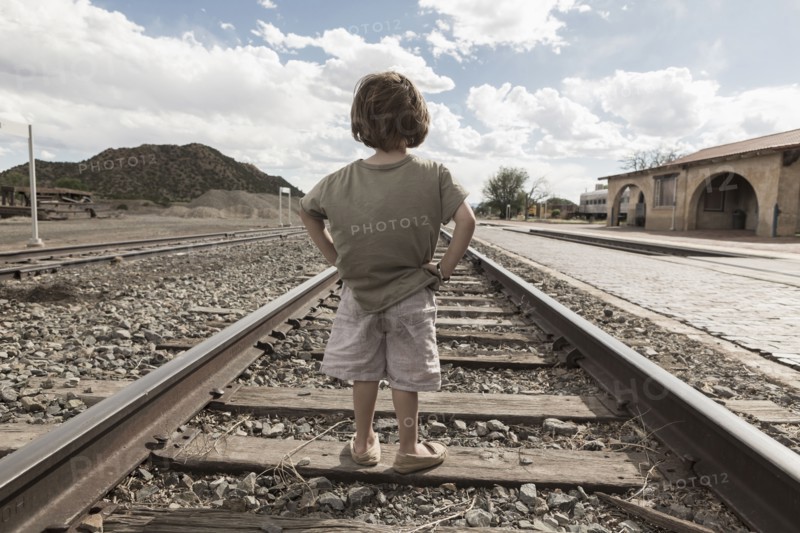 Caucasian boy standing with hands on hips on train track