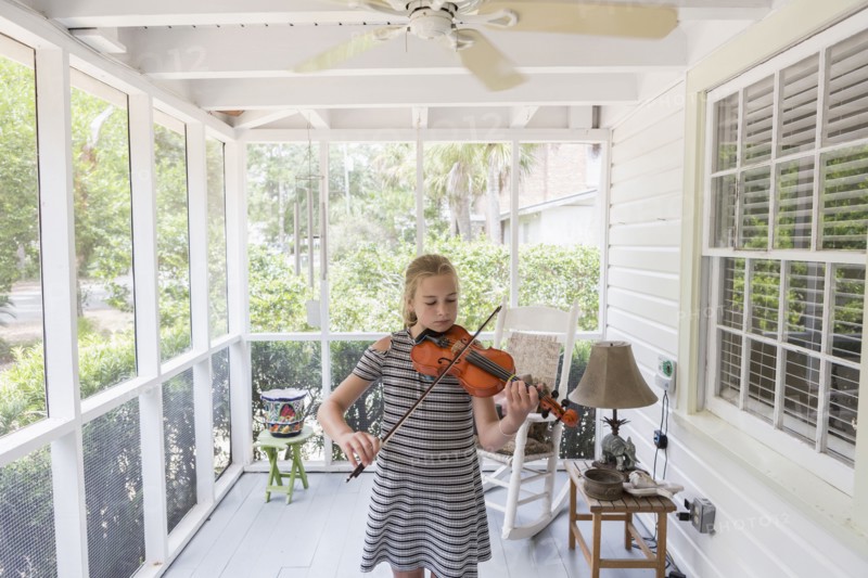 Caucasian girl playing violin on patio