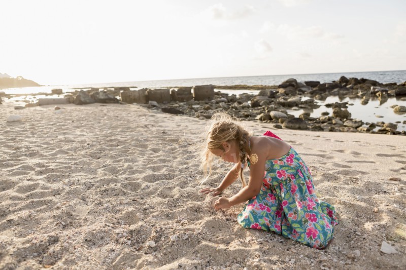 Caucasian girl playing in sand at beach