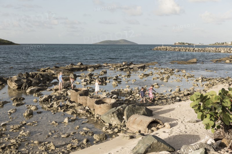 Caucasian boy and girls walking on rocks at beach