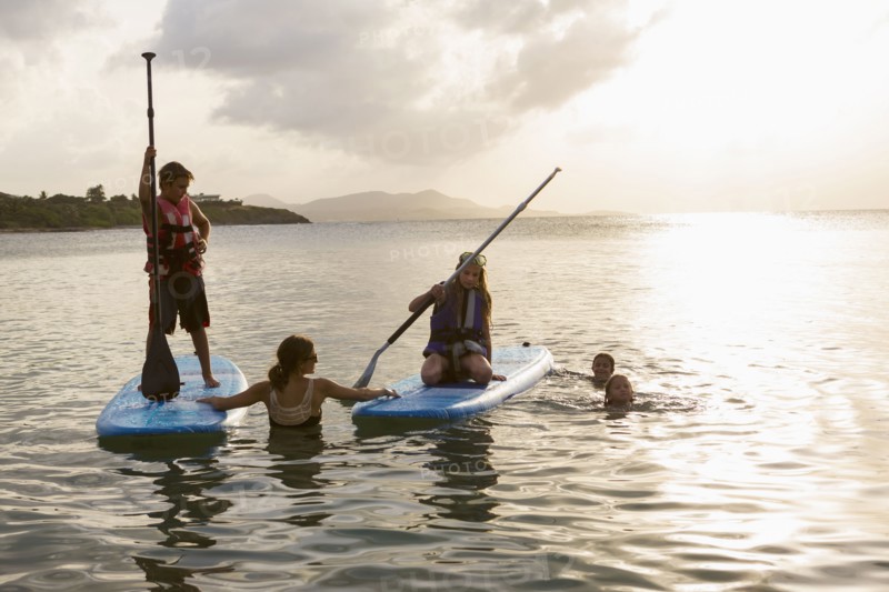 Caucasian family swimming and using paddleboards