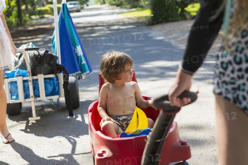 Caucasian boy riding in red wagon