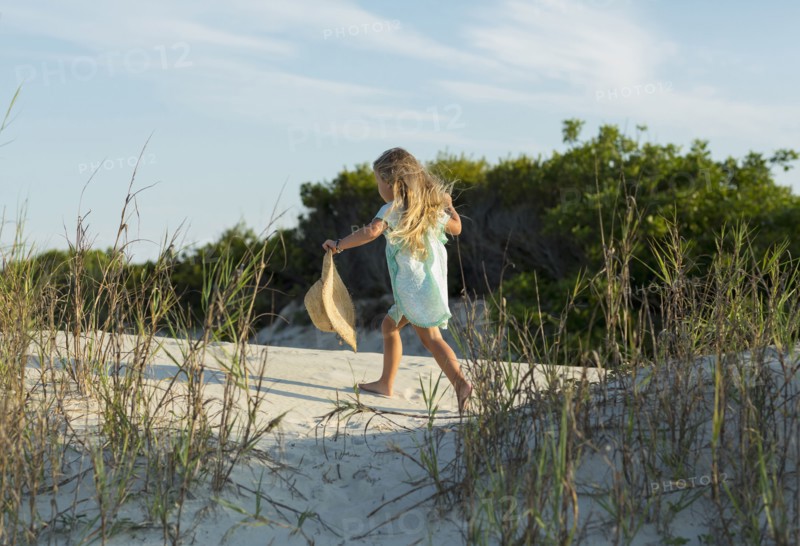 Caucasian girl walking on beach holding hat
