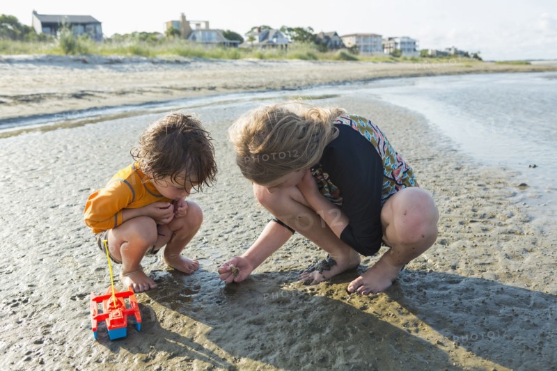 Caucasian brother and sister searching on beach