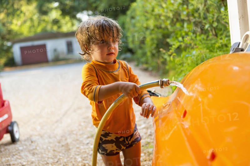 Caucasian boy washing kayak with hose