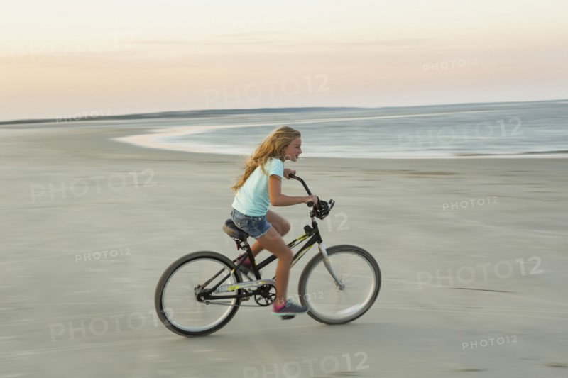 Caucasian girl riding bicycle on beach