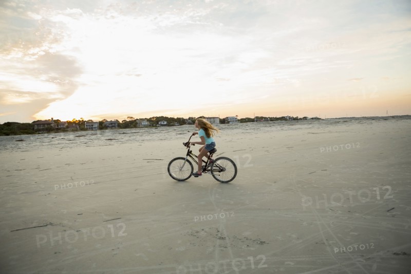 Caucasian girl riding bicycle on beach