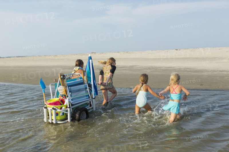 Caucasian boy and girls pulling cart on beach